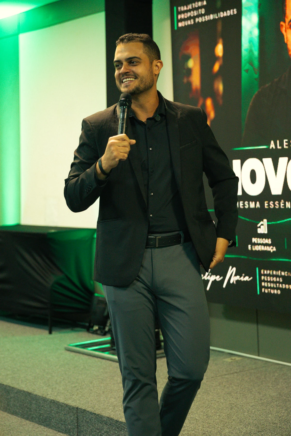 Felipe Maia sorrindo durante uma apresentação, com microfone em mãos